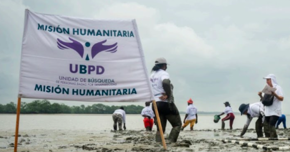 Imagen de personas en una playa con una bandera de Unidad de Búsqueda de Personas dadas por Desaparecidas (UBPD)