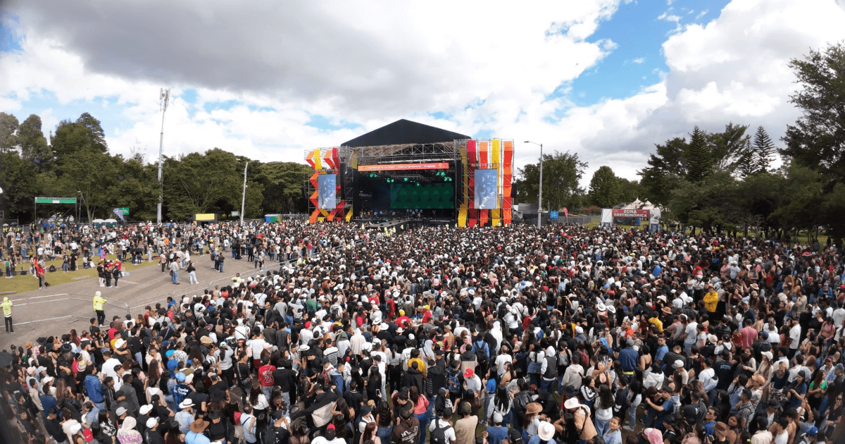 Multitud asiste a concierto masivo al aire libre en el parque Simón Bolívar frente a un gran escenario con pantallas gigantes, zonas de servicios y miles de asistentes reunidos.