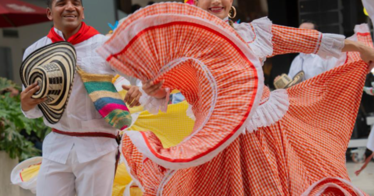 Imagen de un hombre y una mujer que bailan cumbia con sus respectivos trajes típicos.