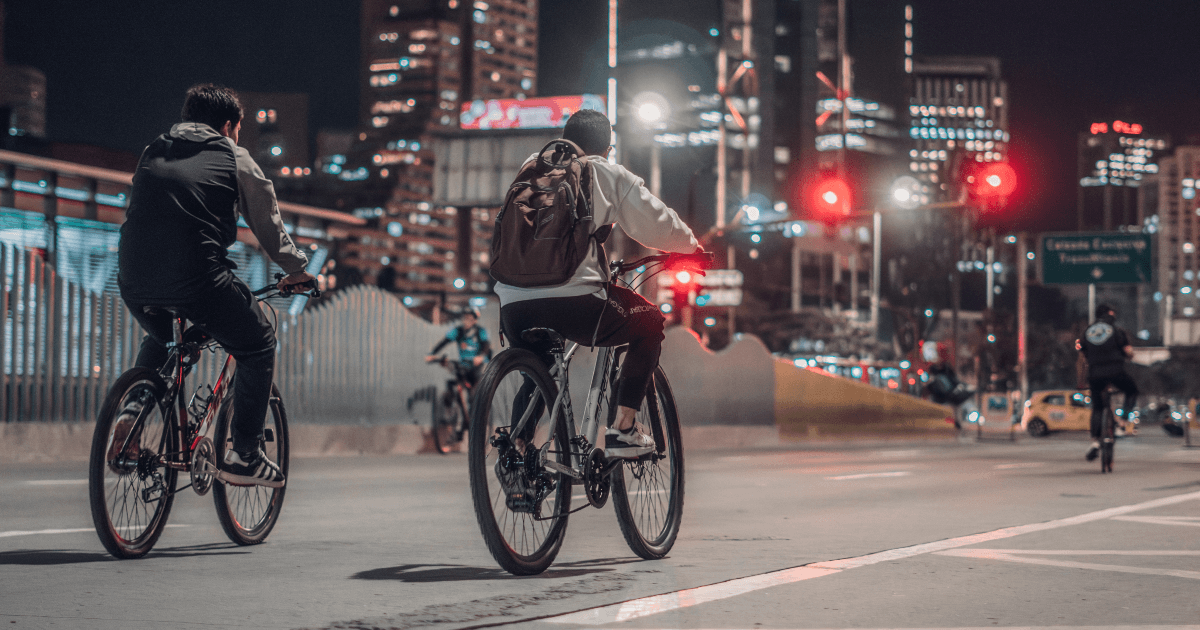 Ciclistas recorren una avenida iluminada de Bogotá durante la noche en actividad de la Ciclovía nocturna