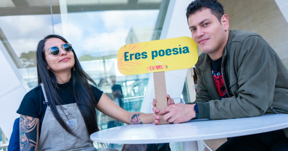 Imagen de dos personas con cartel de Festival reverso 2025