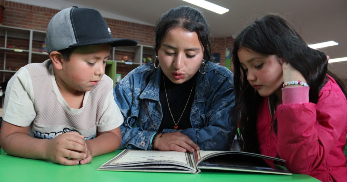 Imagen de 3 niños usuarios de las Bibliotecas Públicas de Bogotá leyendo un libro