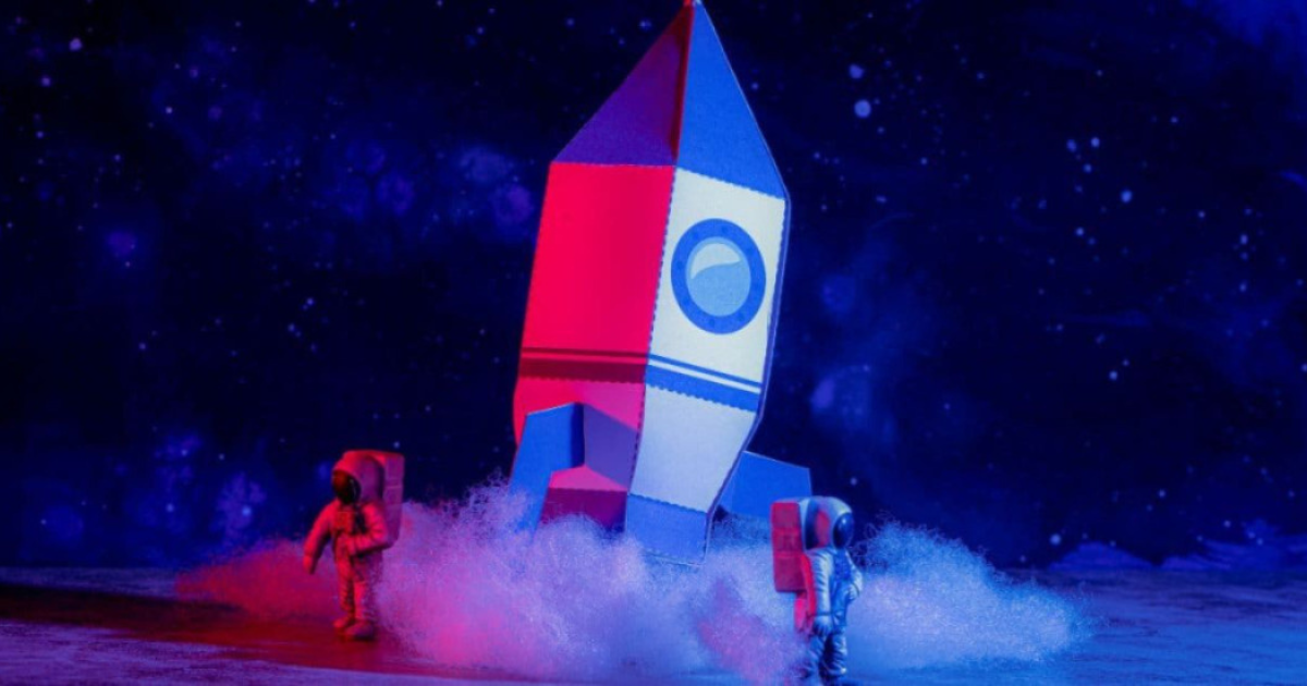 Imagen de cohete en cartón con dos astronautas en escena 