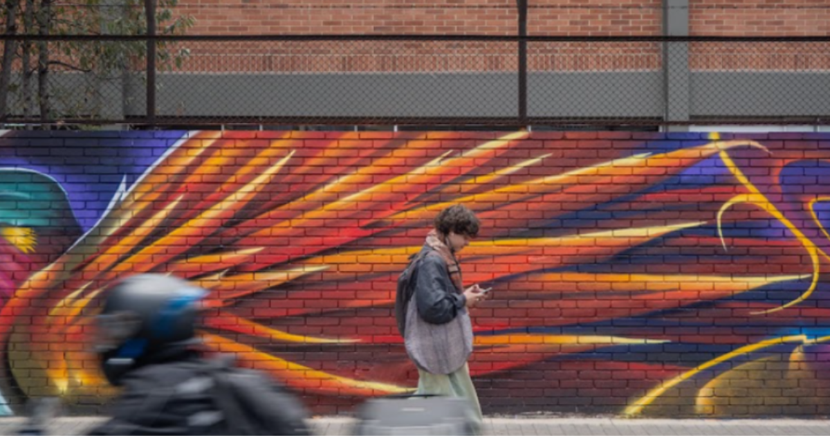 Imagen de un hombre que recorre a pie un mural.