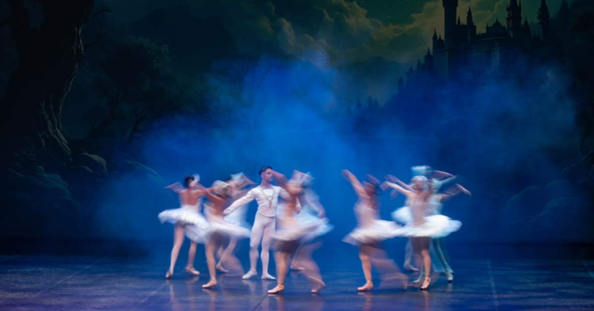 Imagen de una puesta en escena de ballet en la que participan varias mujeres vestidas de blanco y un hombre.