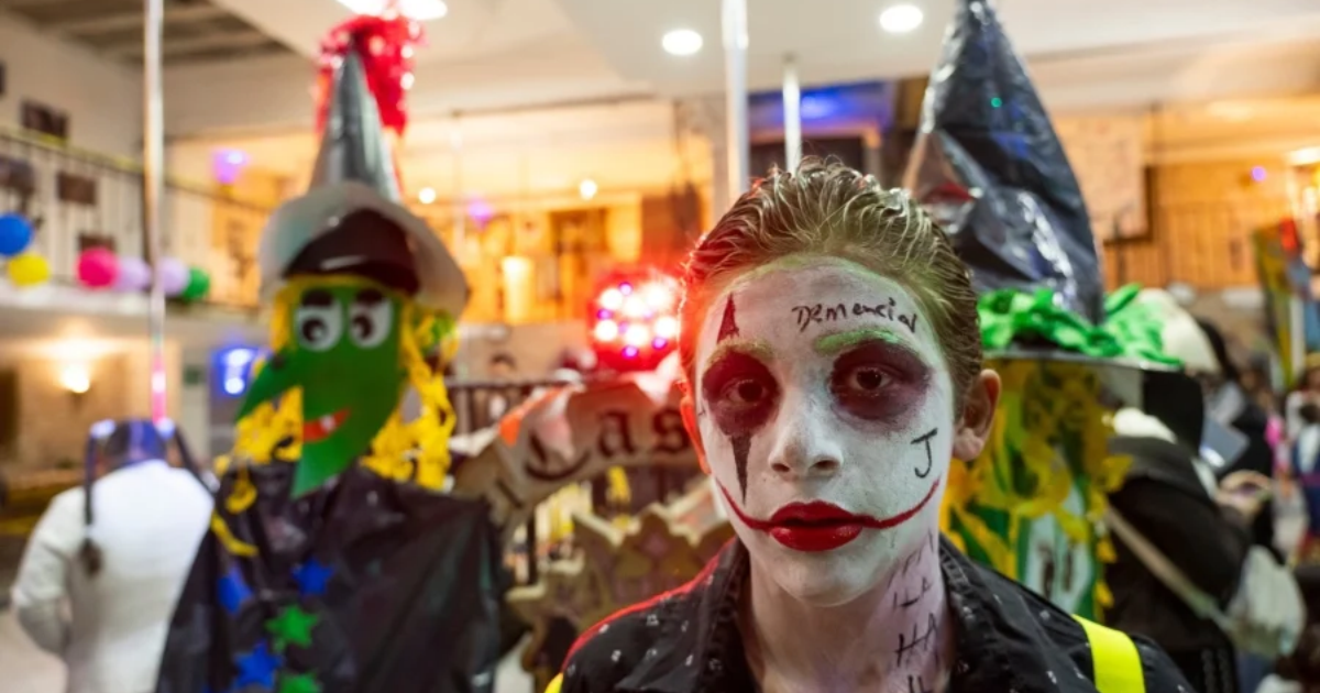 Imagen de un niño disfrasado con su cara pintada, de fondo se ven más niños disfrazados.