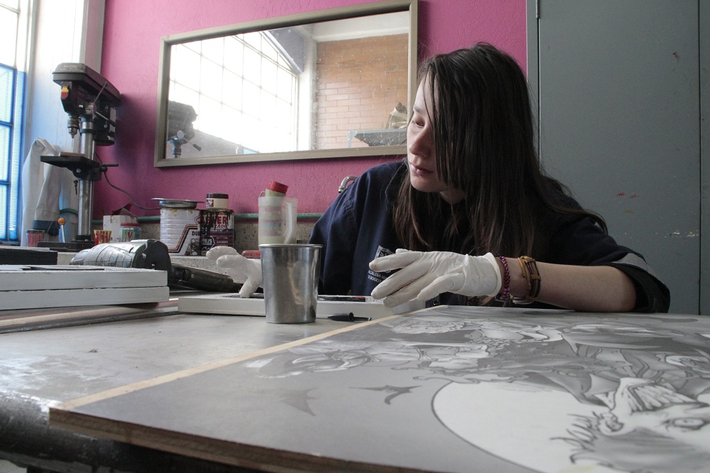 Maritza esparciendo un poco de resina liquida en uno de los cuadros que hace en el taller de ebanistería.