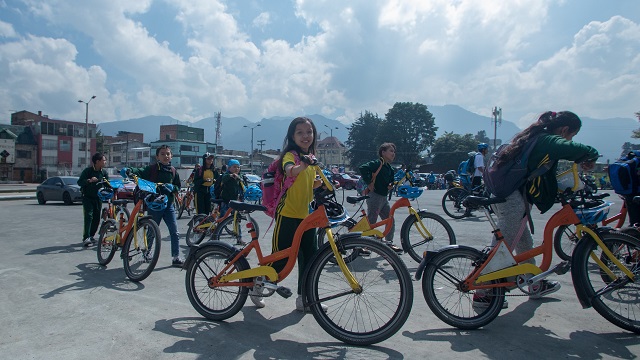 Un grupo de niños cruzando la calle con su bicleta al lado, participando en el programa de movilidad "Al colegio en Bici"