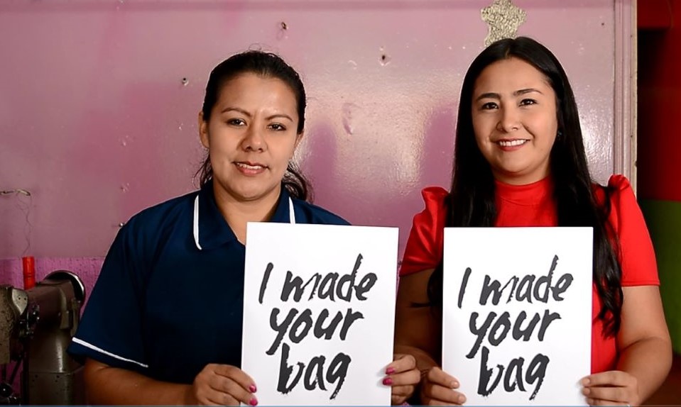Imagen de Paola con un letrero que dice nosotras hacemos tu bolso
