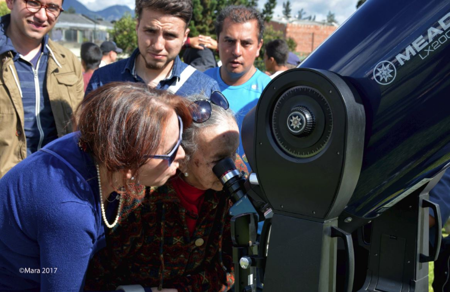 Se encuentran dos mujeres observando por un telescopio 
