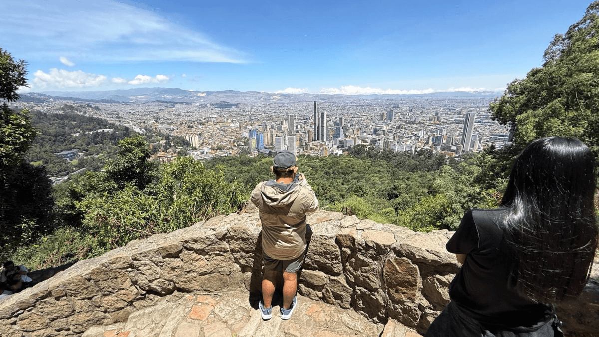 Vista panorámica de Bogotá desde un mirador de Monserrate, rodeado de vegetación.