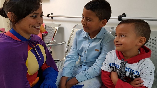 Una enfermera disfrazada hablando con unos niños mientras ellos sonrien