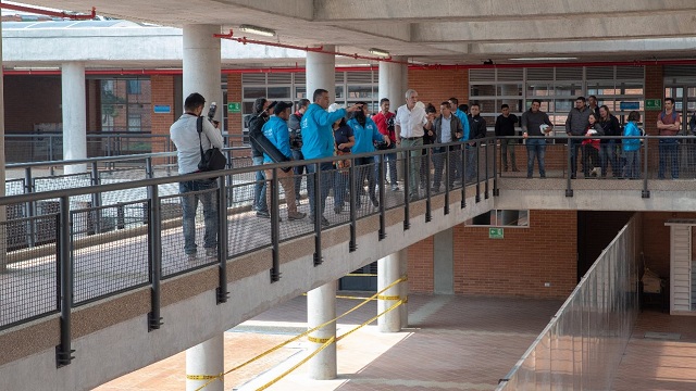 Plano general, el Alcalde Enrique Peñalosa caminando con varias personas alrededor por un pasillo del colegio