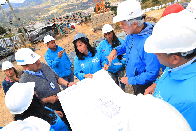 El Alcade Enrique Peñalosa con varios ingenieros en una obra de la ciudad, observando planos de construcción 