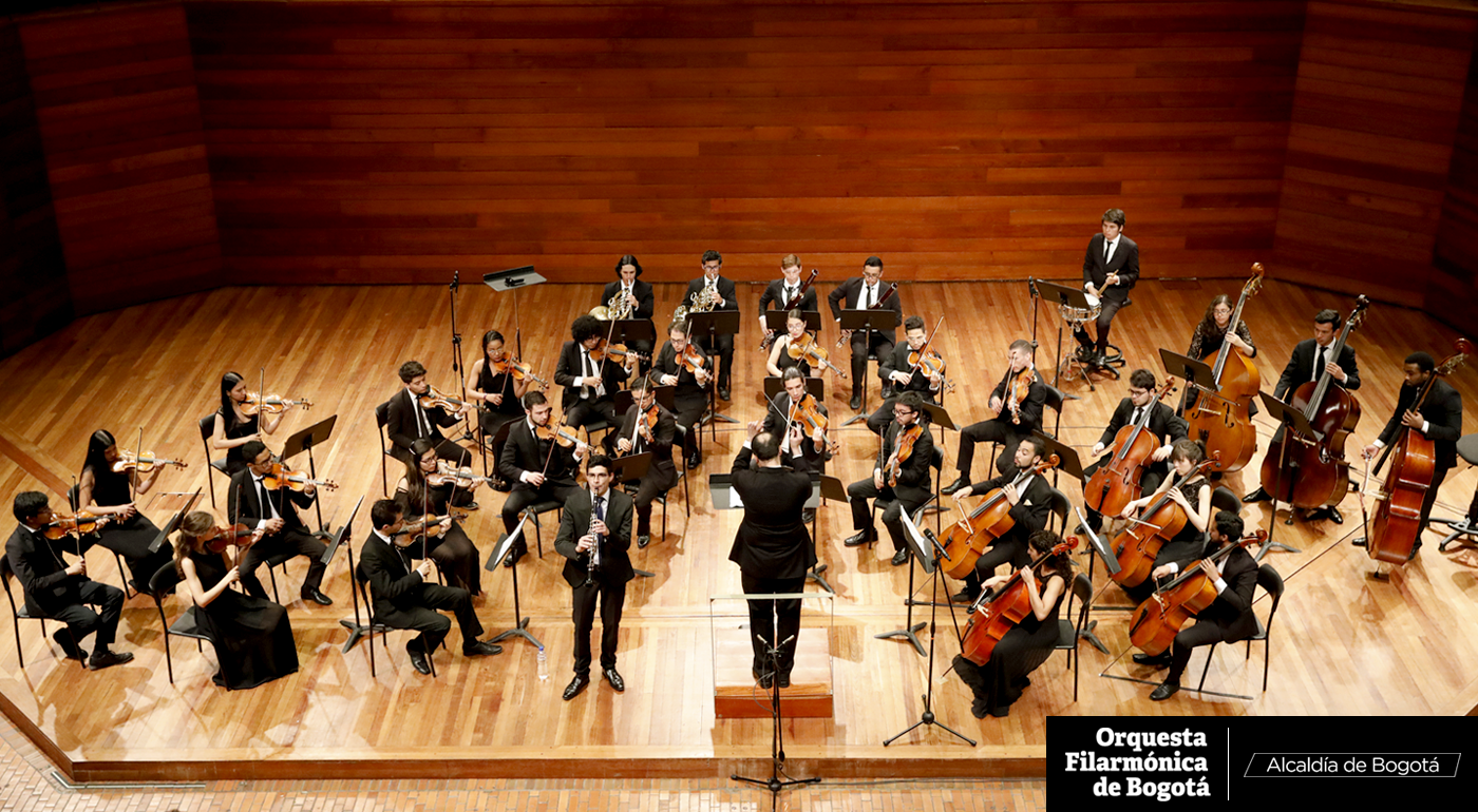Plano general de los miembros de la Orquesta Filarmónica de Bogotá tocando en un escenario