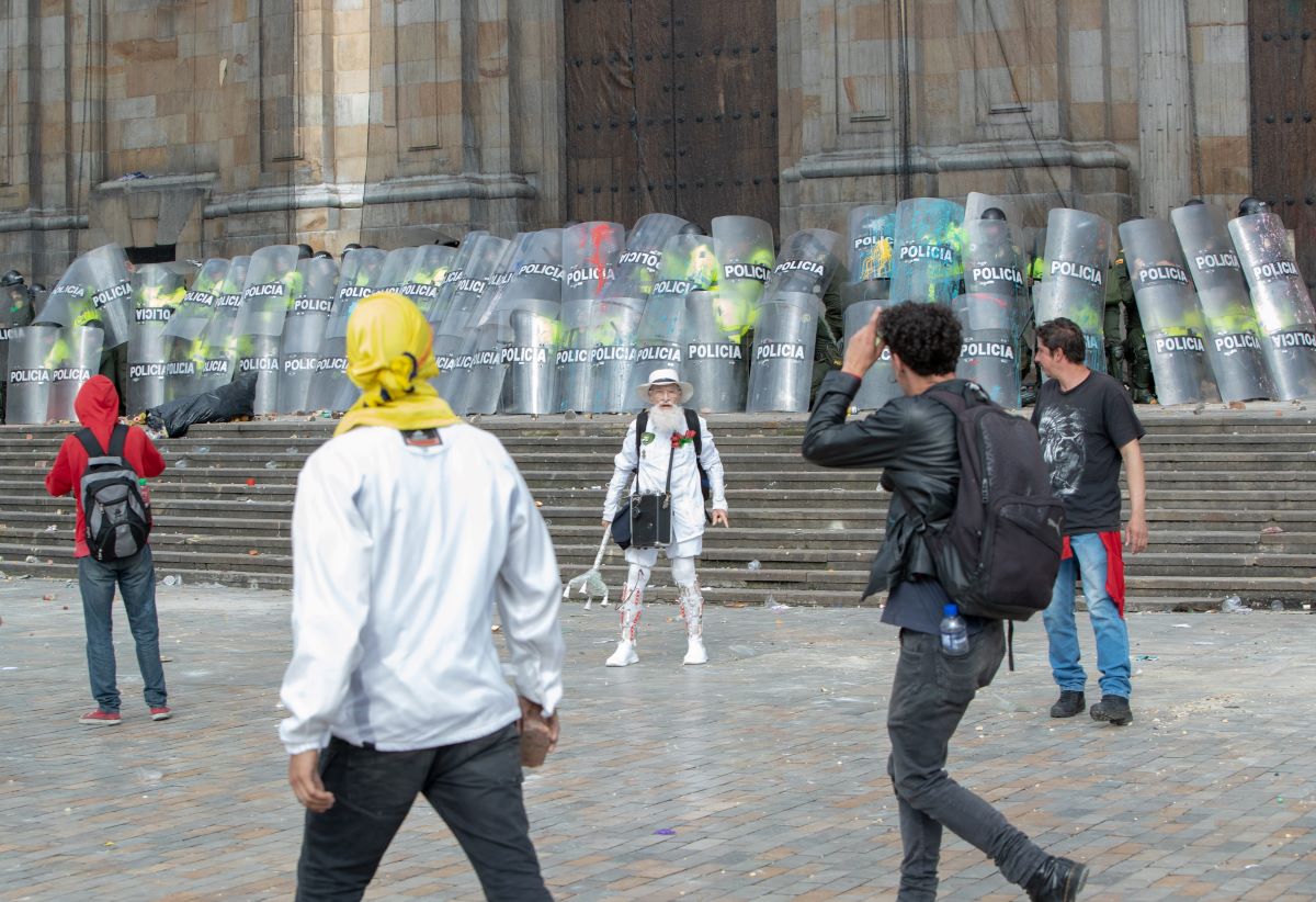 Foto de un hombre vestido de blanco en medio de los disturbios