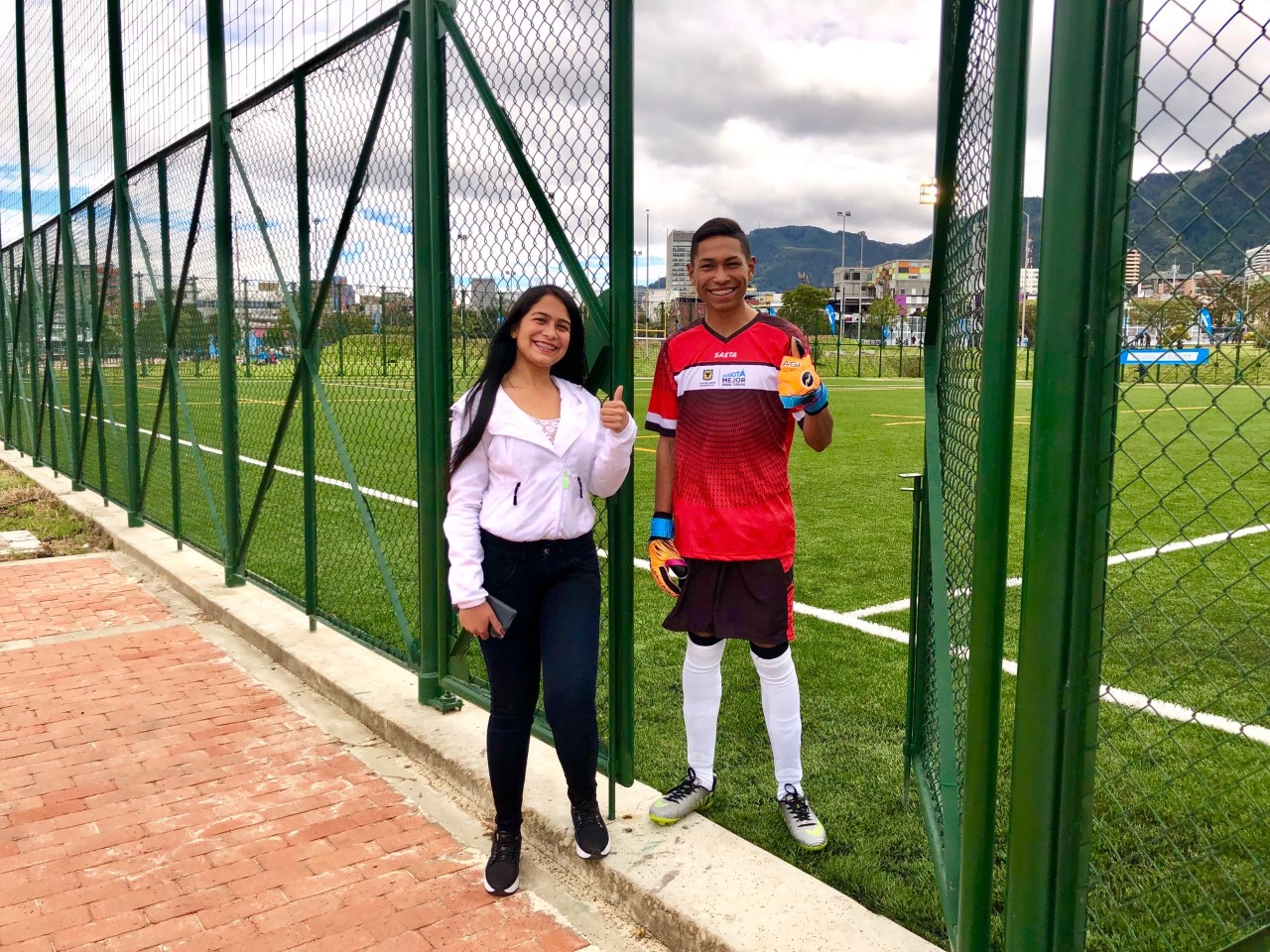 Imagen de Arelys con su hermano, posando en la cancha de fútbol