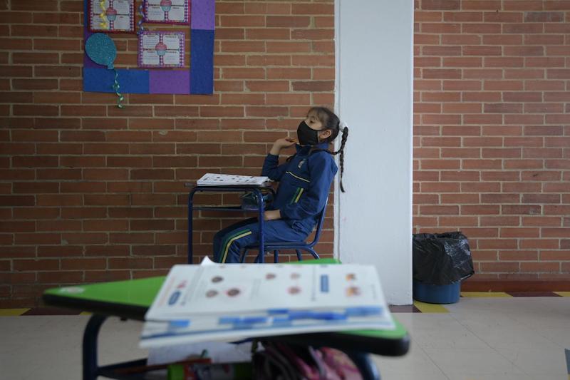 Imagen de una estudiante en salón de clase con tapabocas puesto