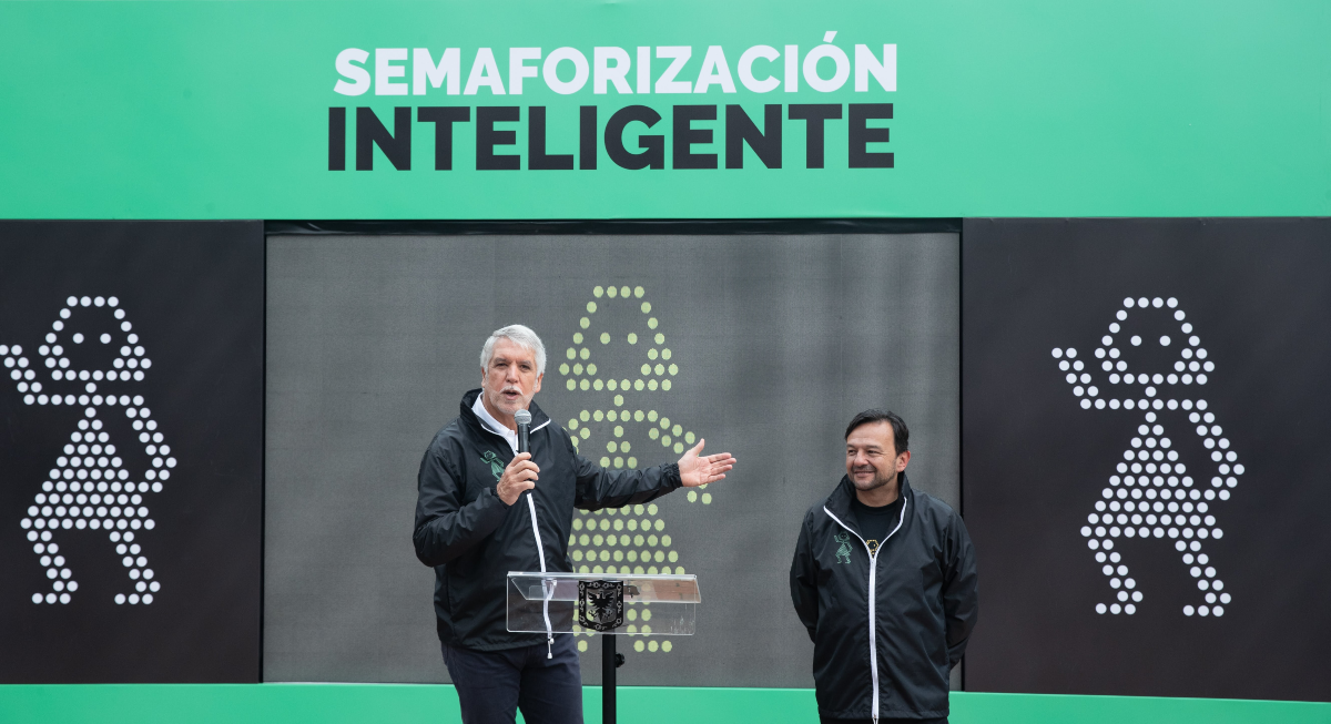 El Alcalde Enrique Peñalosa junto al secretario de movilidad en una tarima hablándole a los ciudadanos sobre la semaforización inteligente
