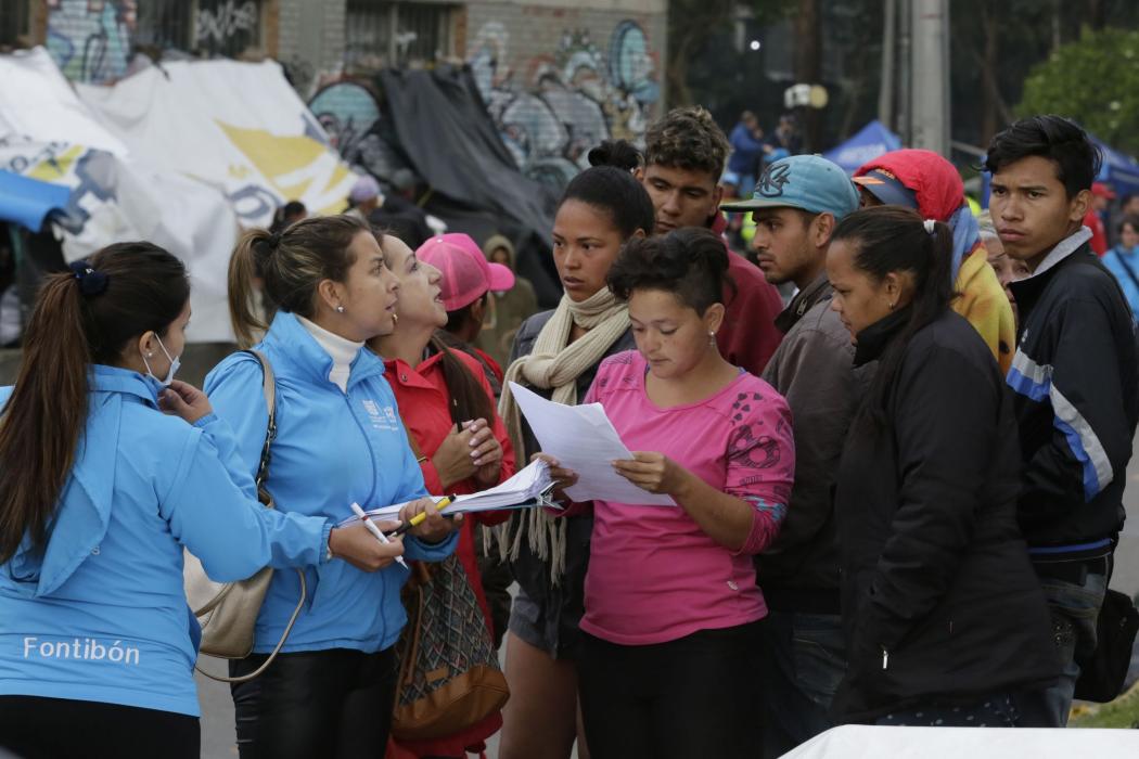 Dos funcionarias de la Alcaldía atendiendo a un grupo de personas, migrantes en el Centro Integral de Atención al Migrant
