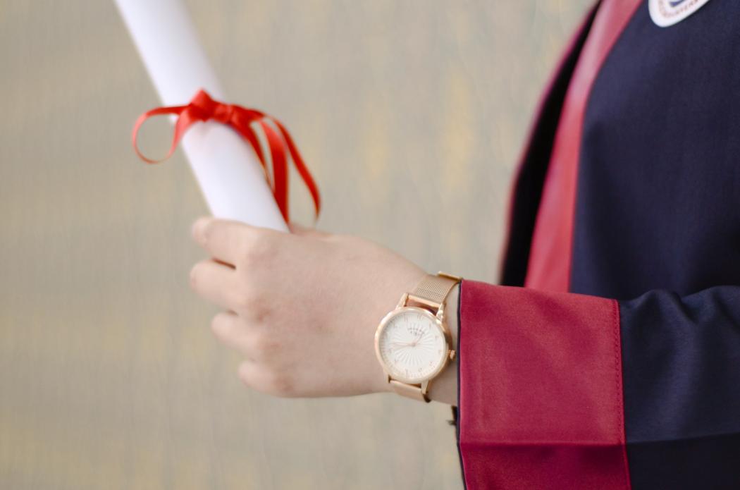 Una persona sostiene un diploma enrollado en su mano