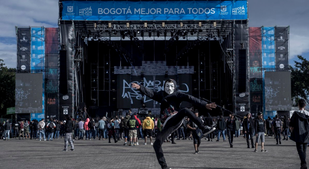 Un joven luce una máscara mientras da un salto delante del escenario principal de Rock al Parque en el Parque Simón Bolívar.