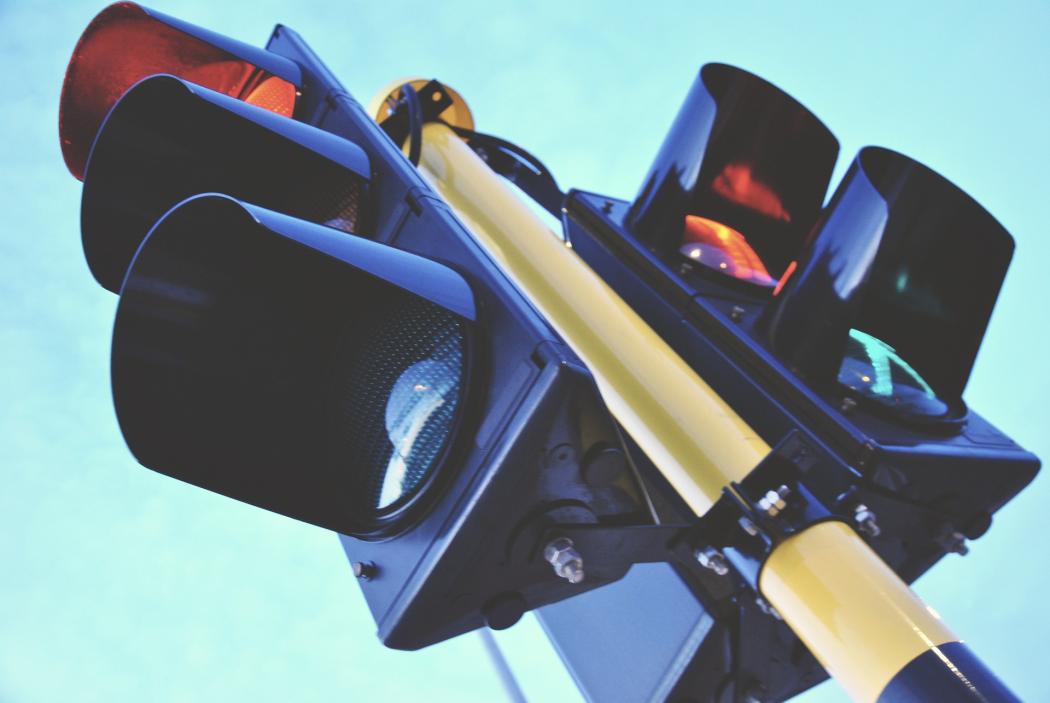 Primer plano de una semáforo, con la luz roja para los vehículos encendida, así como la luz verde para los peatones 