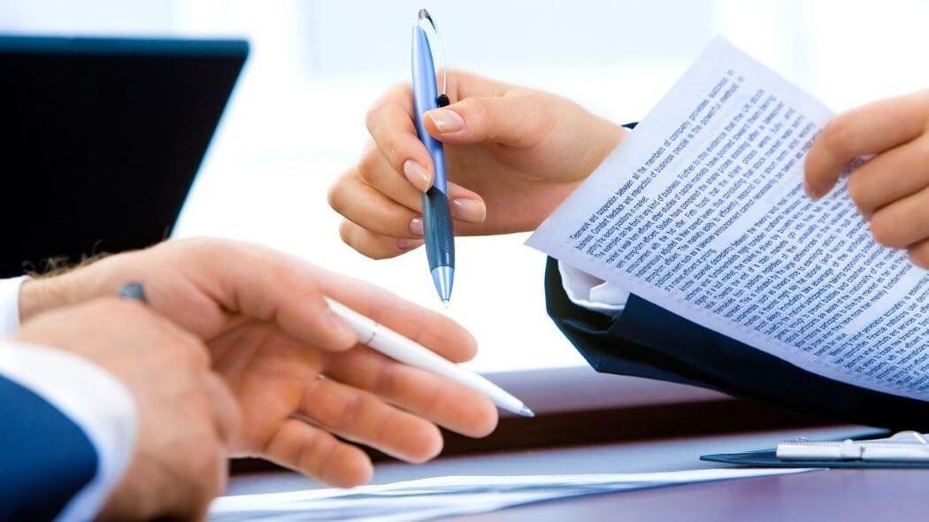 Imagen de dos manos sosteniendo un documento y un esfero.