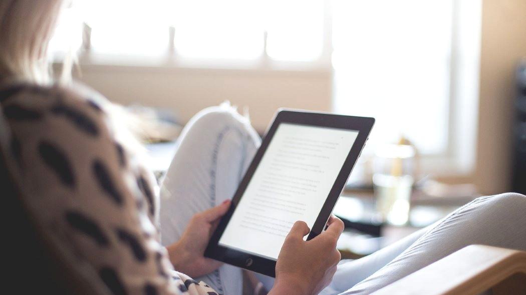 Imagen de una mujer leyendo en una tablet.
