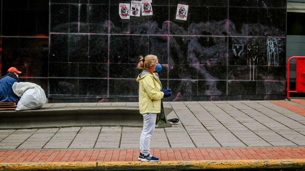 Imagen de una mujer con tapabocas esperando bus.