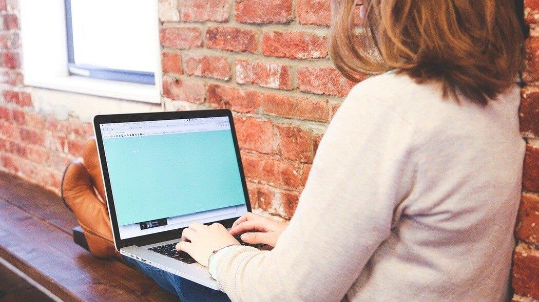 Imagen de una mujer escribiendo en un computador portátil.