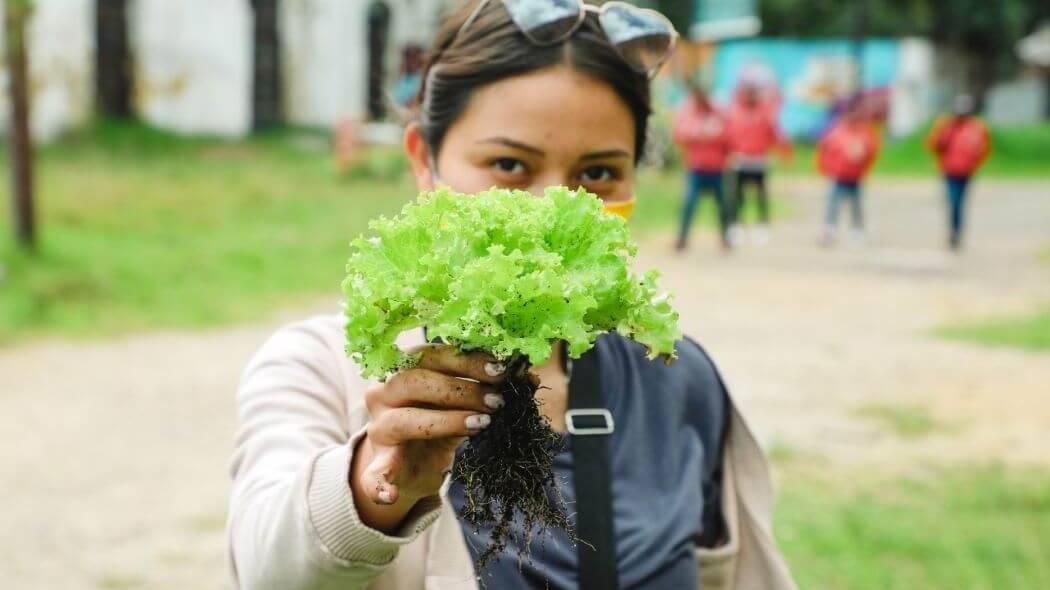 Imagen de una agricultora sosteniendo una planta.