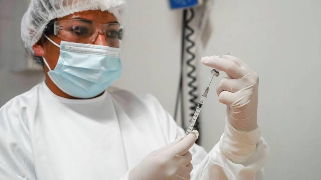Imagen de una funcionaria de salud con la vacuna en sus manos.