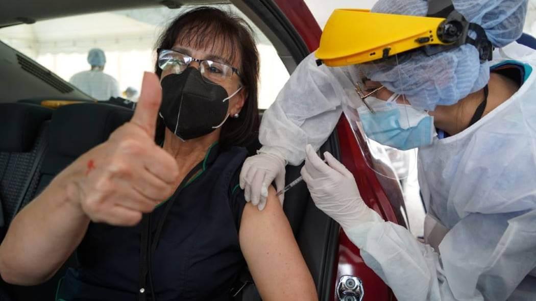 Imagen de vacunación a una funcionaria de salud en su vehículo.