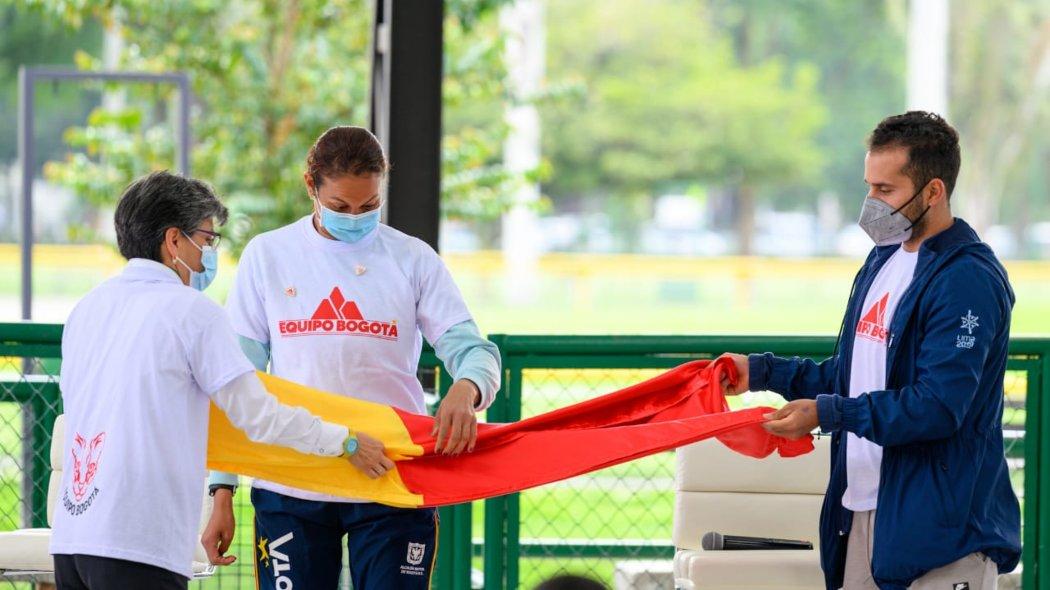 La alcaldesa Claudia López entrega la bandera de Bogotá a la atleta paralímpica Martha Hernández y al ciclista BMX Carlos Ramírez.