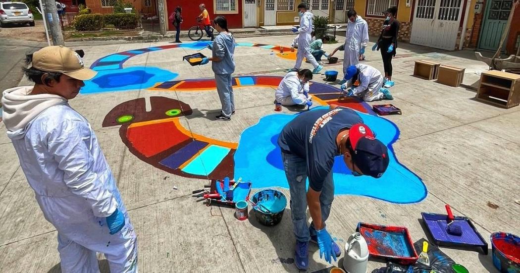 personas pintando arte urbano sobre el piso 