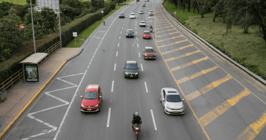 Imagen de vía de Bogotá por donde circulan carros particulares, taxis y moatos.