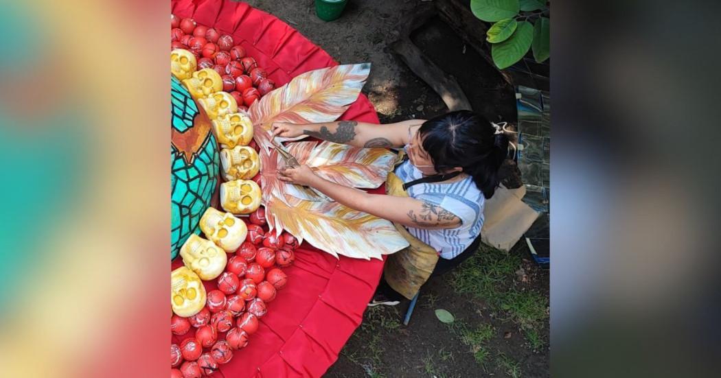 Imagen de una mujer sentada ubicando artesanías sobre un tapete.