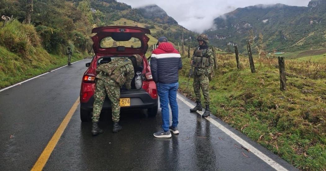Foto de dos soldados realizando verificación a un vehículo y sus ocupantes en una carretera de la zona rural de Bogotá.