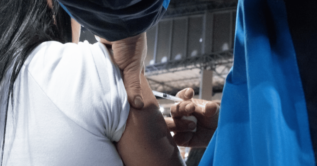 Foto que muestra una mano de una enfermera con una jeringa 