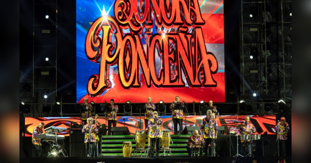 Imagen de la Sonora Ponceña en tarima, atrás suyo se observa una gran imagen con su logo ¨Sonora Ponceña¨ 