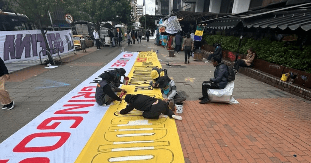 Imagen de personas pintando un cartel en el piso
