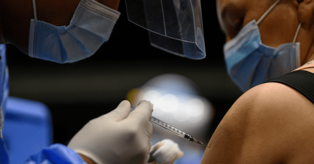 Foto que muestra una persona que le están colocando una vacuna en su brazo