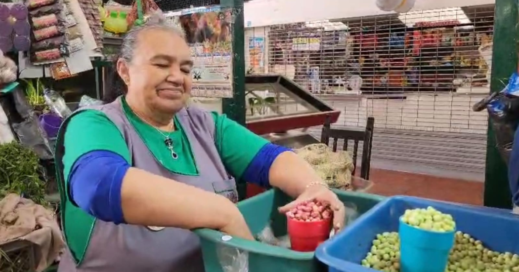 Imagen de vendedora de la plaza organizando los granos