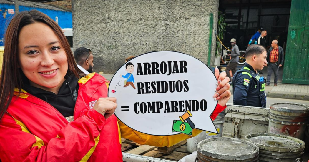Foto de una mujer que sostiene un cartel que advierte “Arrojar residuos = comparendo”