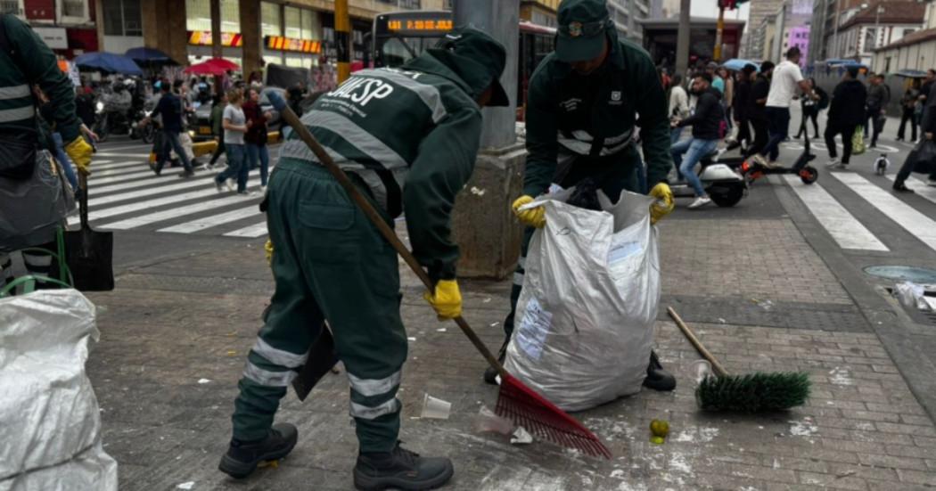 Foto que muestra dos trabajadores de la UAESP levantando basura de las calles