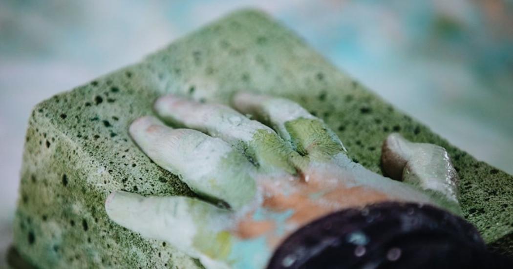 Fotografía de una mano moldeando una piedra