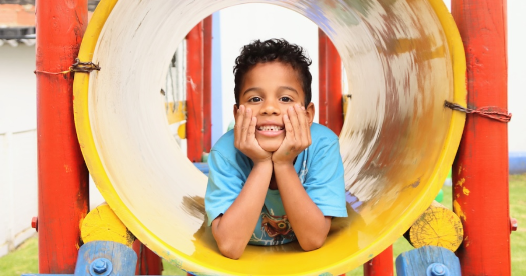 Imagen de un niño sonriendo con las manos en la cara