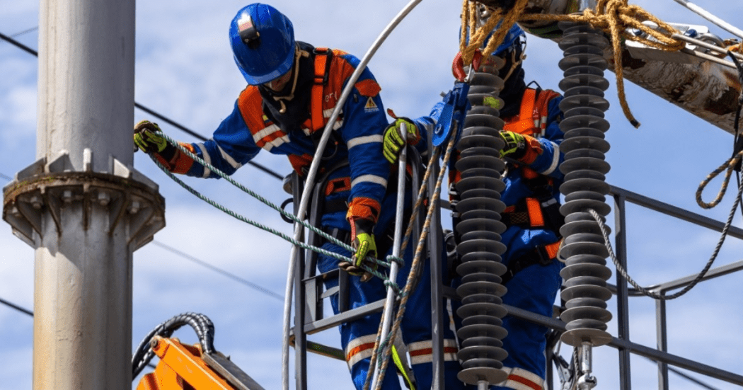 Imagen de técnicos de Enel subidos en un poste de luz realizando trabajos de mantenimiento