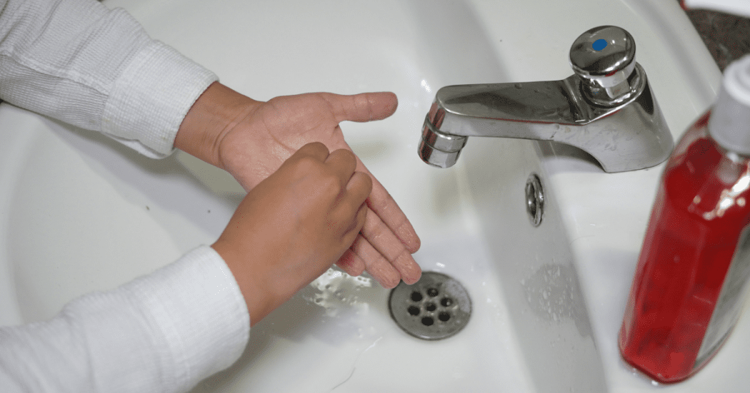 Foto de una persona en proceso de lavado de manos.